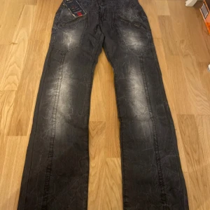 Svarta byxor från Nesal med dragkedjor - Snygga svarta byxor från Nesal i 100% bomull med coolt tvättad look och flera dragkedjedetaljer både fram och bak. Byxorna har raka ben och markerade sömmar som ger en unik stil. Perfekta för dig som vill sticka ut lite extra.