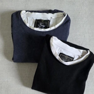 Svart och mörkblå Key Largo tröja M - Två stilrena långärmade tröjor från Key Largo, en i svart och en i mörkblått. Båda har vit kant vid halsen och nederkanten, vilket ger en schysst kontrast. Tröjorna är i mjuk bomull och har en normal passform, perfekta för chill dagar eller när du vill vara enkel men snygg. Djur-och rökfritt hem 