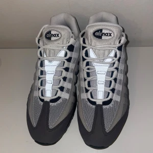 Nike Air Max 95 Grey Gradient  - Nike Air Max 95 sneakers i en clean grå och vit färgkombination med svarta detaljer. Skorna har mesh och mocka på ovandelen. Gav till min kusin som födelsedagspresent, men tyvärr var skorna för småa för honom, Har aldrig använts bara testad av min kusin en gång. Har tyvärr inte kvar original kartongen.