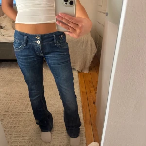 Blå bootcut jeans från LTB - Snygga blå jeans från LTB med låg midja och bootcut passform. Jeansen har dubbla knappar framtill, klassiska fickor och coola söm-detaljer på bakfickorna. Säljer jeansen då dem tyvärr är lite för stora för mig!  Midjemått: ca 40cm Innerbenslängden: ca 82cm