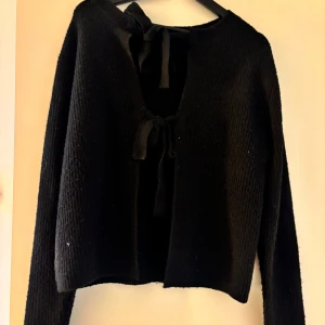 Svart stickad kofta med knyte - Oanvänd stickad tröja med knyte, går att ha både fram och bak 
