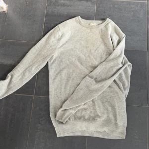 Ljusgrå kashmirtröja John Henric S - Snygg ljusgrå stickad tröja från John Henric i mjuk kashmir. Rund halsringning och ribbade muddar vid ärmslut och nederkant. Perfekt för dig som gillar stilrena och sköna plagg. Passar dig som vill ha en klassisk look med premiumkänsla. Den enda defekten är som man ser på bild tre ett litet hål i en av armbågarna men det är lätt fixat och inget man tänker på så mycket. 100% kashmir, nypris runt 2100 mitt pris 450.