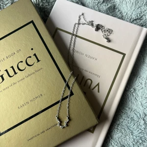 Två silvriga halsband med detaljer - Säljer två snygga silvriga halsband. Det ena har ett hänge med små gnistrande stenar i rad, och det andra har ett stort blommigt hänge med struktur och en liten pärldetalj i mitten. Perfekta accessoarer för att lyfta din outfit. Båda för 80kr