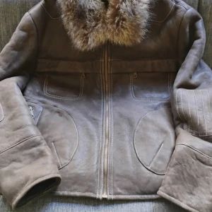 Brun skinnjacka med päls från Soft Leather Geneva. - Riktigt fet brun skinnjacka med mjuk fårull på insidan och stor fluffig päls runt kragen. Jackan har dragkedja framtill, markerade sömmar och stora fickor. Perfekt för kalla dagar när du vill hålla stilen och ändå vara varm..