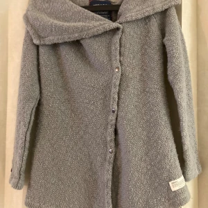 cardigan - Sebago - strM  - Mysig grå stickad cardigan jacka från Sebago med stora slag och knappar framtill. Jackan har lång ärm och en avslappnad passform, perfekt för lager-på-lager. Tjockt stickat material som håller dig varm under kyliga dagar.