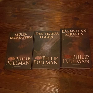 Den mörka materian (Guldkompassen, Den skarpa eggen, Bärnstenskikaren) - Upptäck den episka trilogin 'Den mörka materian'! Följ Lyra och Will på deras farliga äventyr mellan olika världar, där de möter vetenskapsmän, häxor, pansarbjörnar och mörka hemligheter. Böckerna går att köpa sepparat eller tillsammans och är nysskick!