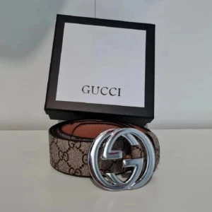 GG Supreme bälte med silverdetalj - Går att pruta Snyggt GG Supreme bälte i brunt med klassiskt monogrammönster och stor silverfärgad GG-spänne. Tillverkat i exklusivt skinn och levereras med originalbox och certifikat. Perfekt accessoar för att lyfta din outfit.