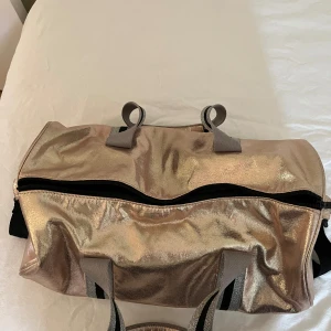 Glittrig guld shoppingväska med axelrem - Snygg och bärbar men det finns en liten fläck på andra sidan.🙂