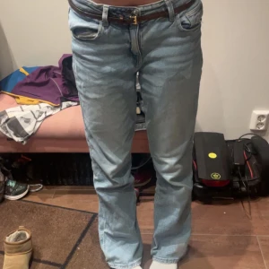 Ljusblå straight jeans - Säljer ett par jeans med rak passform och låg midja. Jeansen har fem fickor, bälteshällor och stängs med knappgylf. Perfekta för en avslappnad och tidlös stil.