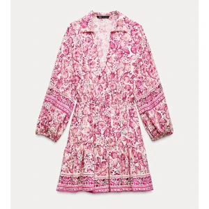 Rosa blommig kortklänning från Zara - Superfin kortklänning från Zara med rosa och vita blommor, volang nertill och långa ärmar med resår. Klänningen har en avslappnad passform och markerad midja. Perfekt för vår och sommar!