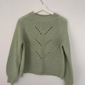 Ljusgrön stickad tröja från Grunt - Superfin ljusgrön stickad tröja från Grunt med snyggt hålmönster framtill. Tröjan har rund hals, ribbade muddar och långa ärmar. Perfekt för hösten. Endast använd fåtal gånger! I barnstorlek L vilket motsvarar xs.