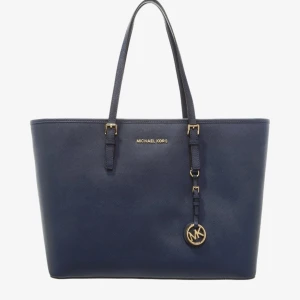 Mörkblå  Michael Kors väska - Stilren mörkblå väska från Michael Kors i skinn med guldiga metalldetaljer och klassisk MK-logga. Väskan har en rymlig insida. Väskan är använd men den är inte sliten. 