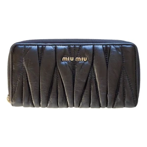 Svart quiltad plånbok från Miu Miu Vintage - Snygg svart plånbok från Miu Miu i äkta skinn med quiltad design och guldfärgade detaljer. Plånboken har dragkedja runtom och flera fack för kort och mynt. Perfekt accessoar för dig som gillar lyxiga detaljer och stilren look.