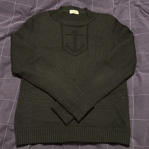Saint Laurent ”Anchor” stickad tröja - Stickad tröja från Saint Laurent med den ikoniska ankare mönstret instucket på tröjan. Väldigt tajt fit då den är gjord på 100% jungfruull, den måste kemtvättas då den får absolut inte tvättas i tvättmaskin. Märkeslappen är lite lossnad, en del av den har blivit bortdraget men den sitter fortfarande kvar stabilt. Kan typ passa både man och kvinna! Hör av er ifall ni har fler frågor, pris kan diskuteras!