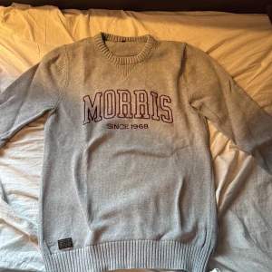 Grå stickad tröja från Morris - En grå stickad tröja från Morris med broderad text 'MORRIS SINCE 1968' i vinrött framtill. 