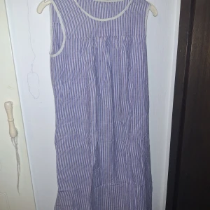 Nattlinne/klänning  - Långklänning med smala vertikala ränder i blått och vitt. Klänningen är ärmlös med rund halsringning och har en luftig, rak passform. Perfekt för varma dagar och enkel att styla med accessoarer. Materialet känns lätt och svalt. Sydd av mamma på slöjden när hon gick i skolan😊🤩