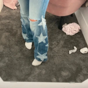 G-Star jeans med stjärnor och slitning - Unika ljusblå jeans från G-Star med stora stjärnor på benen. Modellen har bootcut och en snygg sliten detalj vid knät. Super coola men passar tyvärr inte! W29 L30
