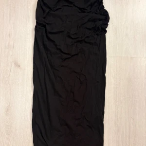 Svart långkjol från Gina Tricot - En svart långkjol från Gina Tricot i enkel och stilren design. Kjolen har en rak passform och är tillverkad i ett mjukt och stretchigt material som sitter bekvämt. Perfekt att matcha med en crop top eller stickad tröja.