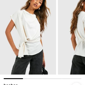 Vit omlottopp med knyt från Boohoo - Snygg vit omlottopp från Boohoo med korta ärmar och knyt i midjan. Toppen har en avslappnad passform och är tillverkad i mjukt material som ger en clean och fräsch look. Helt oanvänd. Inte ens packat upp.  