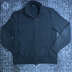 Mörkgrå kofta från Polo Ralph Lauren - Äkta tjock tröja från Ralph lauren. Änvänd men ändå i bra skick. Tröjan är gjord av 100% bomull och är autentisk. Storleken är m. Hör av dig vid frågor eller prisförslag!