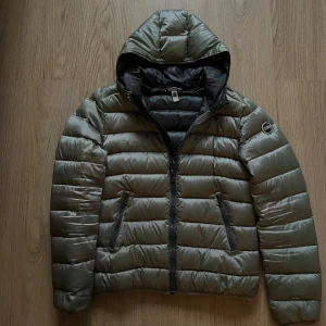 Pufferjacka från Colmar - Snygg pufferjacka från Colmar med huva och två dragkedjeförsedda fickor. Jackan har quiltad design, lång ärm och Colmar-logga på ärmen. Perfekt för kyliga dagar. Storlek 44 Motsvarar XS/S, skick 9/10