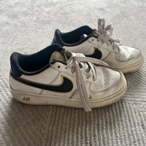 Nike Air Force 1 vita sneakers - Nike Air Force 1 sneakers i vitt med svart och gul detalj på swoosh-loggan🥰