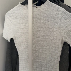 Vit smockad kort klänning - Supersöt vit kortklänning med smockat tyg och korta ärmar. Den har en tight passform och är perfekt för varma dagar. Enkel och stilren design som är lätt att matcha med accessoarer.