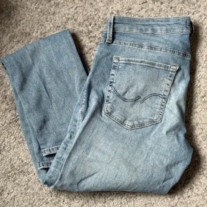 Ljusblå med revor jeans från Jack&Jones - Säljer ett par ljusblå jeans från Jack & Jones i storlek 30x32, modellen Slim/Glenn. Jeansen har klassisk femficksdesign, raka ben och snygga slitningar framtill. Perfekta för dig som gillar en avslappnad och stilren look.