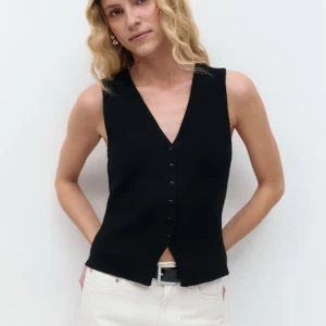 Svart stickad väst från Gina Tricot - Svart stickad väst från Gina Tricot med v-ringning och sju svarta knappar framtill. Oanvänd så väldigt bra skick. stl M 