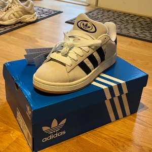 Adidas Campus 00s vita/beiga sneakers - Supersnygga Adidas Campus 00s sneakers i vitt/beige med svarta detaljer och hög sula, svarta skosnören medföljer. Skorna är i nyskick med lappar och ariginalkartong som medföljer. Nypris ca 1 400kr, mitt pris 1 000kr✨Hör av dig vid frågor eller önskemål om fler bilder❣️