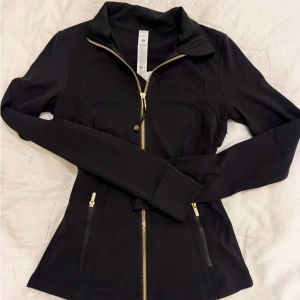  Lululemon define jacket - Snygg svart jacka från Lululemon med guldiga dragkedjor och figurnära passform.. 💕