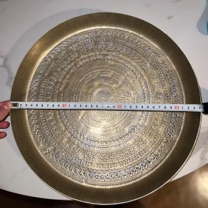 JYSK Dekorativ Bricka Guld - Elegant dekorativ bricka i guld från JYSK. Vackert mönstrad yta, perfekt som serveringsbricka eller inredningsdetalj. Fint skick, endast mindre spår av användning. Utrustad med skyddande fötter undertill för stabil placering.