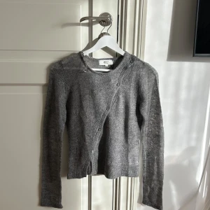 Asymmetrisk grå kofta XS - Säljer en grå asymmetrisk kofta från Gina i stickad bomullsblandning. Koftan har lång ärm, knappar i sned knäppning, den är perfekt nu till hösten🥰