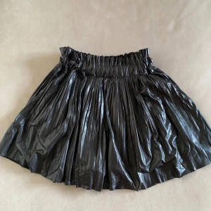 Skort/byxkjol - Zara - Säljer en svart plisserad skort/byxkjol med resår i midjan. Kjolen har en voluminös look och inbyggda shorts under för extra komfort. 