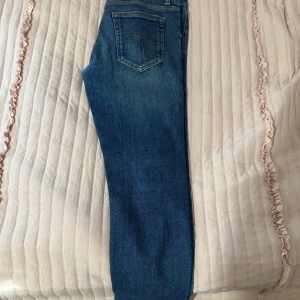 Tiger jeans Slim blå jeans 28/32 Made in Italy - Slim fit jeans i klassisk blå tvätt med snygga slitningar och fem fickor. Byxorna har dragkedja och knappstängning, tillverkade i Italien. Passar dig som gillar en smal siluett och vill ha ett stilrent och tidlöst plagg i garderoben.