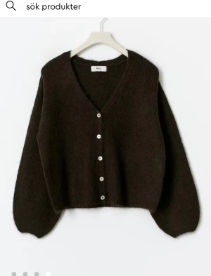 Mörkbrun kofta  - Mysig mörkbrun kofta från Gina Tricot med v-ringning och knappar framtill. Koftan är stickad och har långa ärmar med lätt puffad form. Perfekt för att ge din outfit en chill och trendig vibe. Slutsåld!!!