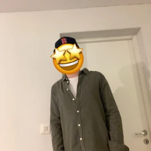 Grön skjorta med knappar - Snygg grön linne skjorta med klassisk krage och vita knappar hela vägen. Skjortan har lång ärm och en loose passform som ger en chill vibe. Perfekt att bära över en t-shirt för en avslappnad stil. Materialet linne, vilket gör den skön och lätt.