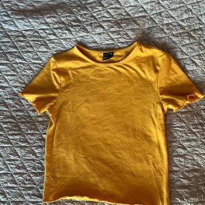 Gul t-shirt från Gina Tricot XS - Snygg gul t-shirt från Gina Tricot i storlek XS. Modellen har rund halsringning och korta ärmar med lätt vågad kant. Materialet är mjuk bomull som känns skönt mot huden. Perfekt för dig som gillar färg och enkel stil. Kort i modellen 