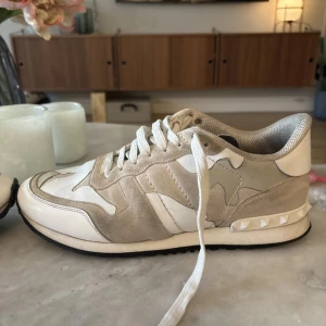 Valentino Rockrunner  - Säljer ett par Valentino Rockrunner sneakers i beige och vitt med camouflage-mönster. Skorna har snörning, rund tå och detaljer i mocka och skinn. Klassisk Valentino-logga på plösen och nitar på hälen. Kommer med originalkartong. Och kvitto, priset är inte hugget i sten vid snabb affär så kan jag sänka 