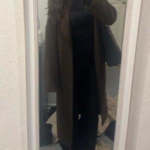 Brun kappa - Brun lång kappa från bershka. Använd en vinter. Bra skick. Går även att stänga med knytband. 