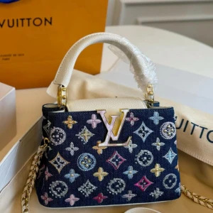 Louis Vuitton broderad handväska(L&S) - Snygg handväska från Louis Vuitton med broderade monogram i pastellfärger på mörkblått och svart tyg. Väskan har en metallkedja, stort LV-emblem framtill och handtag i skinn. Perfekt för dig som vill sticka ut med lyxig design och coola detaljer.