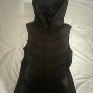 Svart quiltad dunväst från Zara - Svart dunväst från Zara med huva. Har lite fläckar på luvan. Har ett hål vid fickan och dragkedjan är sönder.