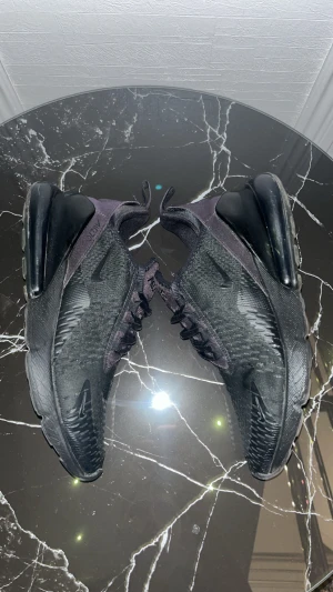 Nike Air Max 270 svarta sneakers - Svarta Nike Air Max 270 sneakers med mesh-ovandel och synlig Air-enhet i hälen. Snygg sportig design med snörning och platt sula. Perfekt för dig som gillar en enkel daglig stil, eller att ha på sig dem överlag och vill ha bekväma skor med modern look. 