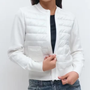 Vit quiltad kofta med dragkedja - Snygg vit kofta med quiltad framsida och två fickor. Tröjan har långärmade ribbade ärmar, rund halsringning och stängs med dragkedja. Perfekt för lager-på-lager och ger en clean look till jeans eller kjol.