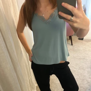 Ljusblå/grön  linnetopp med spets - Säljer en ljusblå linnetopp med v-ringad hals och dekorativ spetskant. Toppen har en loose passform som känns chill och enkel att bära. Perfekt för varma dagar eller att styla lager på lager.