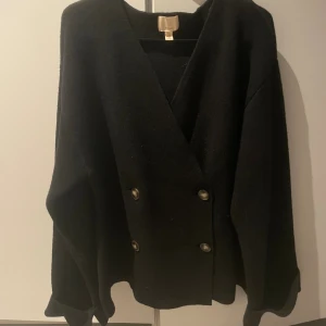 Svart kofta med v-ringning och knappar - Snygg svart kofta från H&M premium. Den är i nästan 100% ull och väldigt varm och härlig! Nypris är 1500