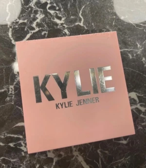 Kylie Jenner Pressed Blush Baddie - Säljer en Kylie Jenner Pressed Blush Powder i färgen 335 Baddie On The Block. Rougen kommer i en snygg ljusrosa fyrkantig dosa med spegel och har en varm persikotonad nyans. Perfekt för att ge kinderna en fräsch och naturlig glow. använd endast 2-3 gånger 