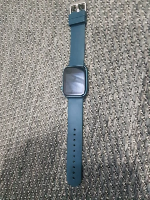 Blå smartklocka med silikonarmband - Snygg smartklocka med fyrkantig display och blått silikonarmband. Klockan har en modern look med metallfärgad ram och justerbart spänne i silver. Perfekt för dig som gillar tech och vill ha koll på tiden med stil. Kommer med laddare men utan kartong använt bara några gånger.