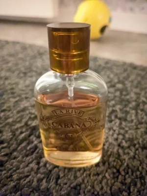 La Rive Cabana parfymflaska - La Rive Cabana är en parfym med stilren flaska och gyllene färg. Perfekt för dig som vill sticka ut med en unik doft. Passar dig som gillar att testa nya parfymer och vill ha något annorlunda i samlingen.