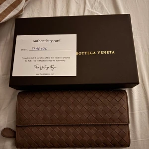Brun plånbok från Bottega Veneta - Snygg brun plånbok från Bottega Veneta i flätat skinn. Plånboken har flera kortfack, en dragkedja och klassisk design med lock. Perfekt för dig som gillar stilrena accessoarer med lyxig känsla. Aldrig använd och knappt slitage. 